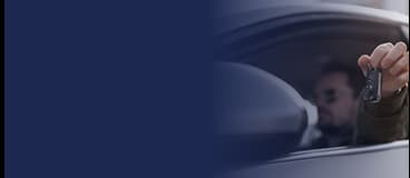 Homem de terno segurando chave de um carro